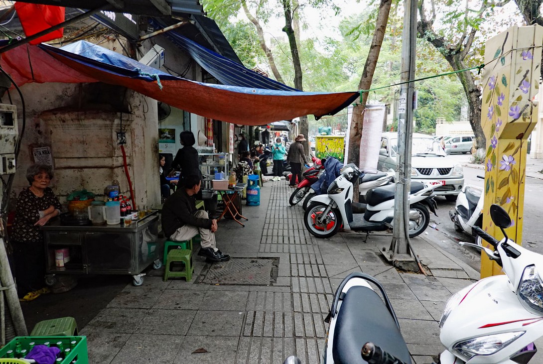 Motorroller und Straßenrestaurants auf dem Bürgersteig in Hanoi